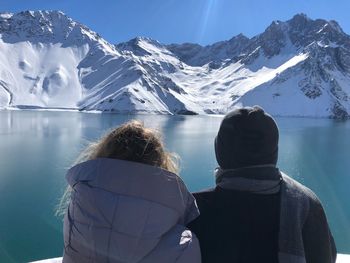 Rear view of friends in warm clothing looking at snowcapped mountains