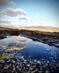 Surface level of lake against sky during sunset