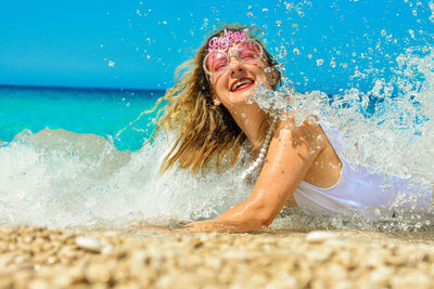 Close-up of smiling young woman lying on shore at beach