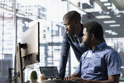 Young man using laptop while standing in office