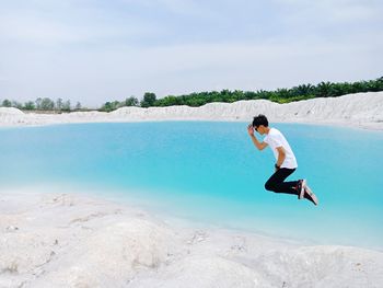 Man jumping in sea against sky