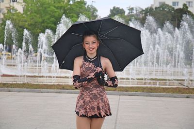 Full length of a smiling young woman standing in rain