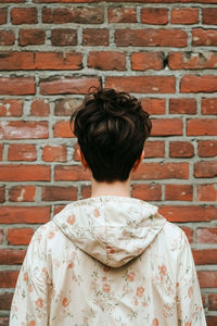 Portrait of woman standing against brick wall