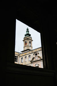 Low angle view of clock tower amidst buildings against sky