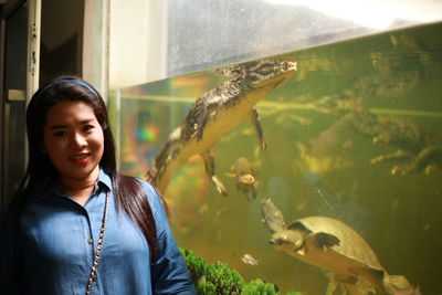 Portrait of woman standing by crocodile in fish tank