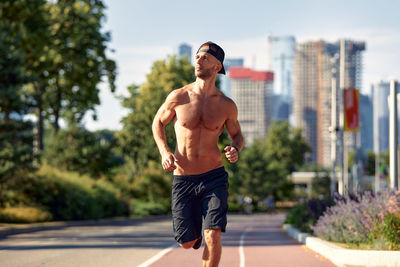 Rear view of shirtless man exercising on road