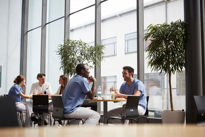 Smiling multi-ethnic medical team sitting at cafeteria in hospital