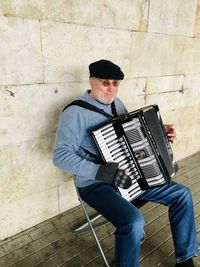 Full length of man playing piano against wall
