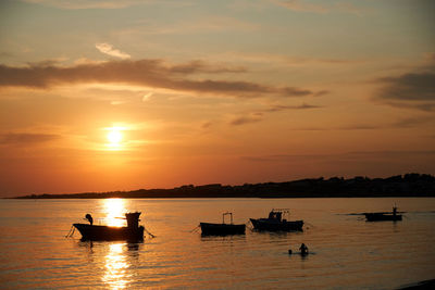 Silhouette boats in sea against sky during sunset