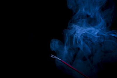 Close-up of incense burning against black background