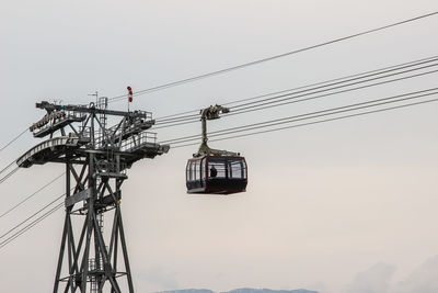 Low angle view of overhead cable car against sky