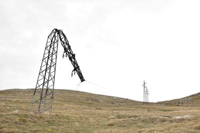 Low angle view of electricity pylon on field against sky