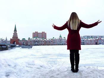 Rear view of woman standing on snow covered cityscape