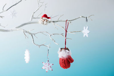 Little red mitten, snowflakes and santa claus hang on bare tree branch 