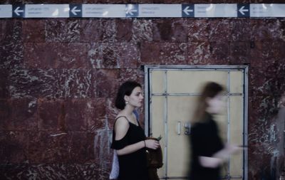 Young woman walking by wall