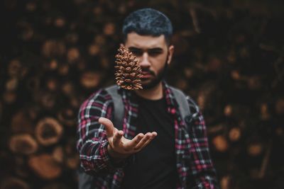 Young man playing with pine cone while standing outdoors