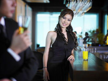 Young woman looking at businessman drinking at bar