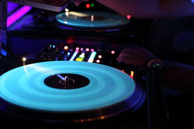 Cropped hands of dj using sound mixer in nightclub