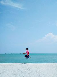 Man sitting at beach against sky