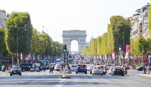 Cars on city street by arc de triomphe against clear sky