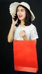 Portrait of woman wearing hat against black background