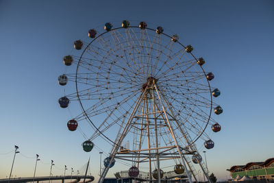 Low angle view of ferris wheel against clear blue sky