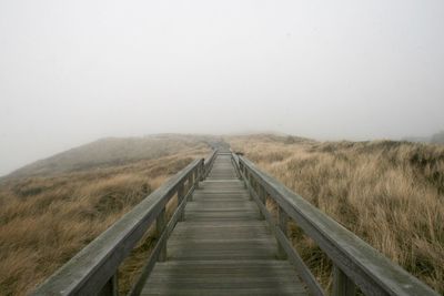 Boardwalk on landscape against clear sky