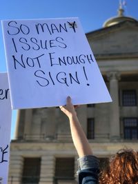 Woman holding text on paper against building in city