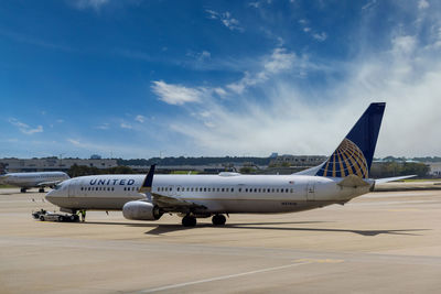 Airplane on airport runway against sky