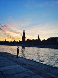 Silhouette of man with city in background at sunset