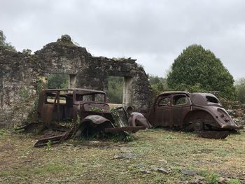 Abandoned car on field against sky