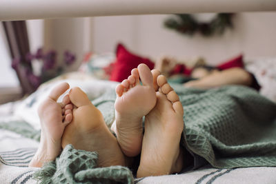 Low section of baby lying on bed