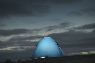 Luminous tourist tent against the background of the evening sky. the theme of hiking