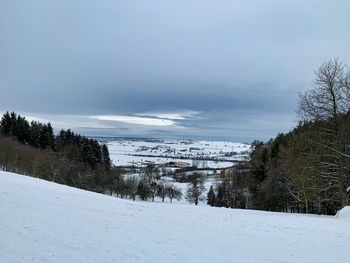 Snow covered land and trees against sky