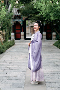 Portrait of young woman walking on footpath in park