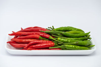 Close-up of red chili peppers in plate against white background