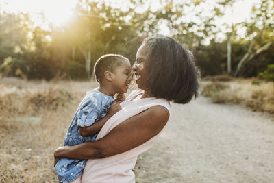 Close up of happy grandmother holding young granddaughter in sun