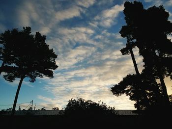 Low angle view of silhouette trees against cloudy sky