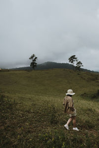 Woman walking on field against sky