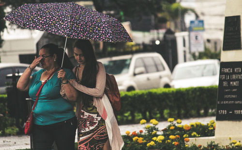 Woman holding umbrella while standing in rain