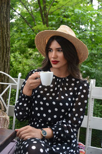 Young woman drinking coffee while sitting at porch 