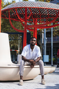 Full length portrait of young man sitting outdoors