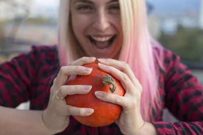 Close-up of cheerful young woman squeezing food outdoors