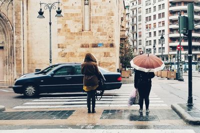 Rear view of people walking on wet street in rainy season