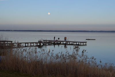 People on pier against sky at dusk