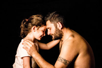 Young couple kissing against black background