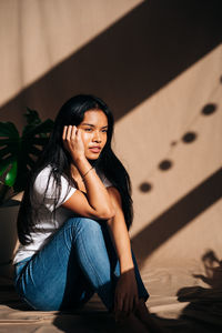 Portrait of woman sitting against wall