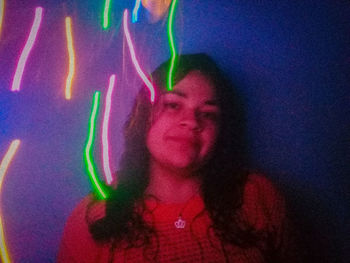 Portrait of young woman on illuminated fabric at night