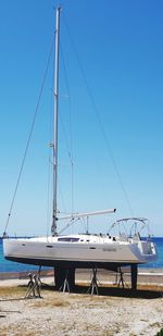 Sailboats moored at harbor against clear blue sky