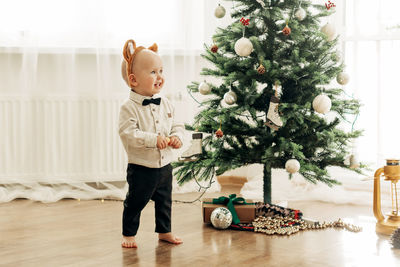 Funny boy in a sweater and tiger ears on the background of a christmas tree. the symbol of the year